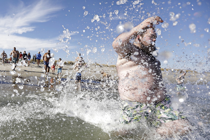 Tyler O'Driscoll sends water flying into the air as he and fellow participants jump into the cold waters off Gooseberry Island in Westport, MA during the annual Plunge of the Faithful.  The event is held in memory of Shannon O'Driscoll who was killed in 2006 by an SUV driver while holding a sign supporting organized day care programs in the state. This is part of a fundraiser, which has raised over 30K dollars since it began.  PHOTO PETER PEREIRA