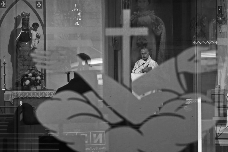 Franciscan Father Andre conducts noon mass as seen through the etched glass door of Our Lady's Chapel in downtown New Bedford, MA. PHOTO PETER PEREIRA