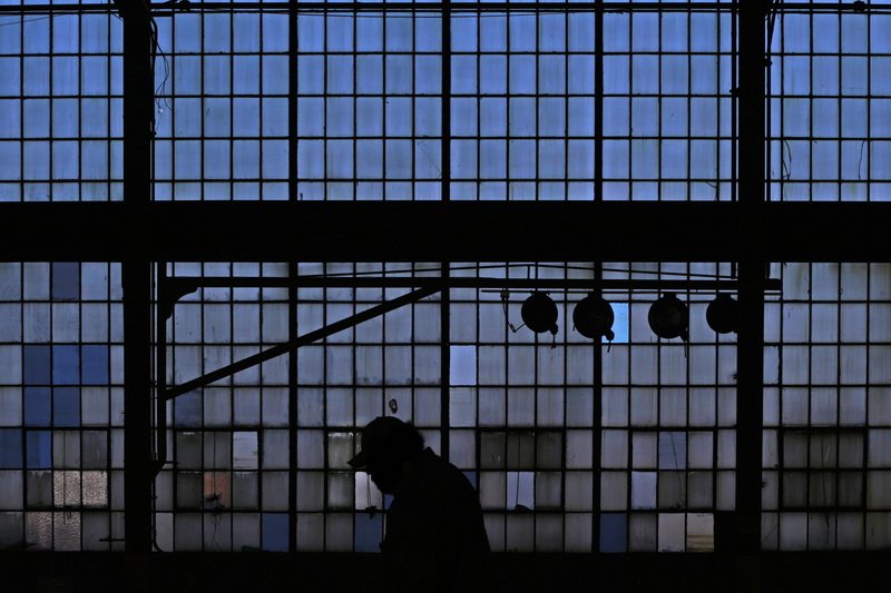 A worker walks past the historic glass pane wall of the former Revere Copper plant in New Bedford, MA which is now the Shoreline Offshore maritime yard. PHOTO PETER PEREIRA