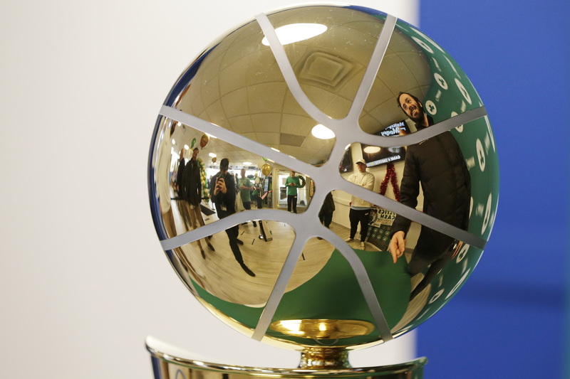 Fans are reflected on the Celtics 2024 NBA Champion trophy as they take photos with it during its stop at the Mass State Lottery office at the Industrial Park in New Bedford. PHOTO PETER PEREIRA