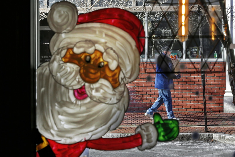 A Santa painted on the windows of Cafe Arpeggio in downtown gives a man a hand walking up Purchase Street in downtown New Bedford, MA on a cold morning.  PHOTO PETER PEREIRA