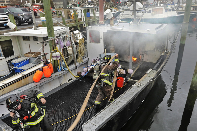 New Bedford firefighters arrive on the scene to respond to a fire aboard a small lobster boat docked in New Bedford, MA.  PHOTO PETER PEREIRA