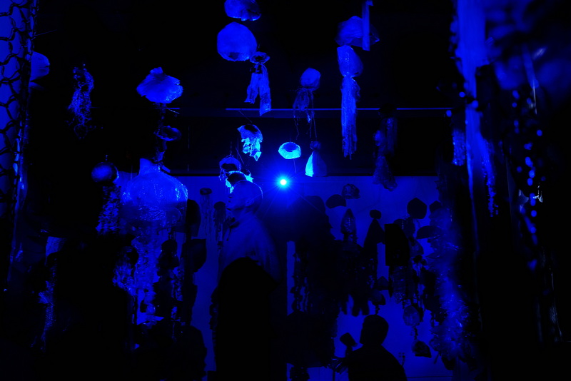 A visitor to the New Bedford Whaling Museum is cast in a blue hue as 'jellyfish' made from discarded plastic bags hang from the ceiling in a new exhibit by Katy Rodden Walker entitled Community Blooms. The exhibit puts emphasis on the plastic being one of the most prevalent types of marine debris found in waterways.  PHOTO PETER PEREIRA