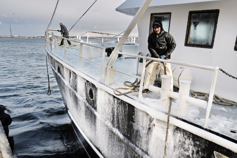 Tyler Hutchens, engineer, and fellow crewmembers of the fishing boat Liberty tie off at theWhaling City Seafood Display Auction dock after arriving covered in ice after twelve days at sea in extreme cold temperatures. PHOTO PETER PEREIRA