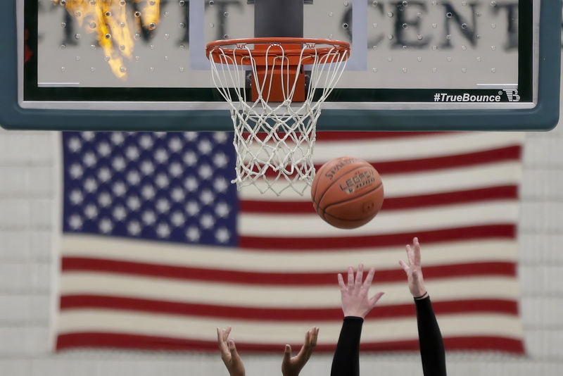 An American flag hangs on the wall in the background as players go up for the rebound during Dartmouth High School against Durfee High School in girls basketball.  PHOTO PETER PEREIRA