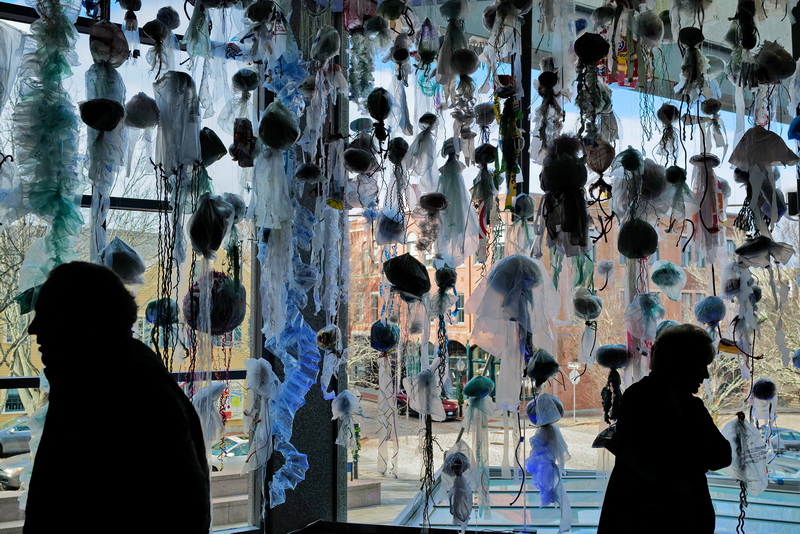 Visitors to the New Bedford Whaling Museum take a closer look at the 'jellyfish' made from discarded plastic bags hanging from the ceiling in a new exhibit by Katy Rodden Walker entitled Community Blooms. The exhibit puts emphasis on the plastic being one of the most prevalent types of marine debris found in waterways. PHOTO PETER PEREIRA