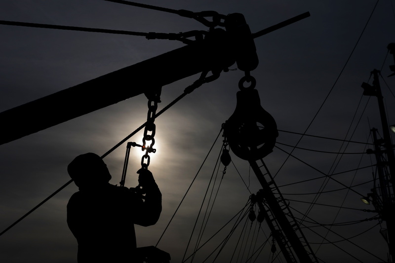 Ryan Peterson, mate of the fishing boat Saints & Angels, uses a welding torch to heat up the shackle to help remove it to install a new chain on the outrigger of the fishing boat docked in New Bedford, MA as the sun rises on a frigid day. PHOTO PETER PEREIRA