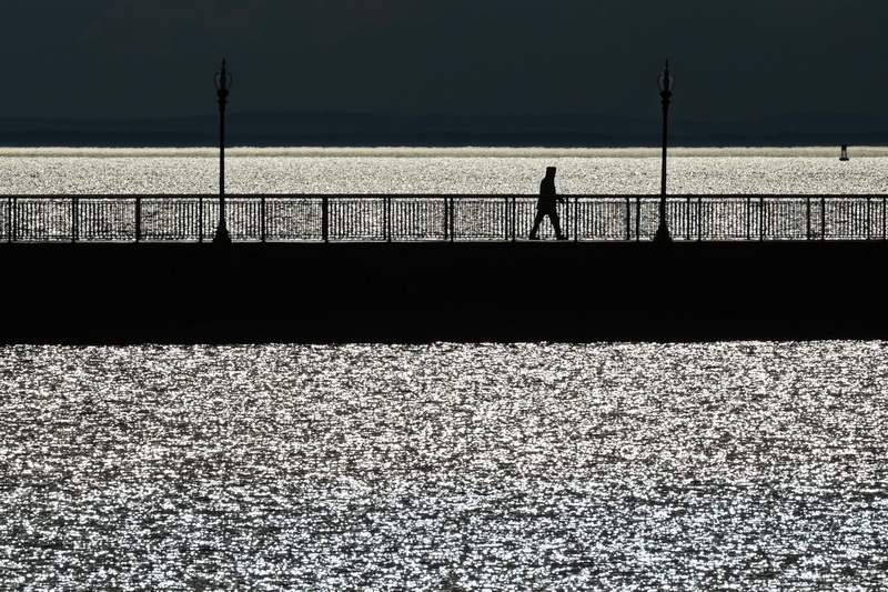 A man makes his way across the Fort Taber Park pier in New Bedford, MA as the early morning sun glistens on the water. PHOTO PETER PEREIRA