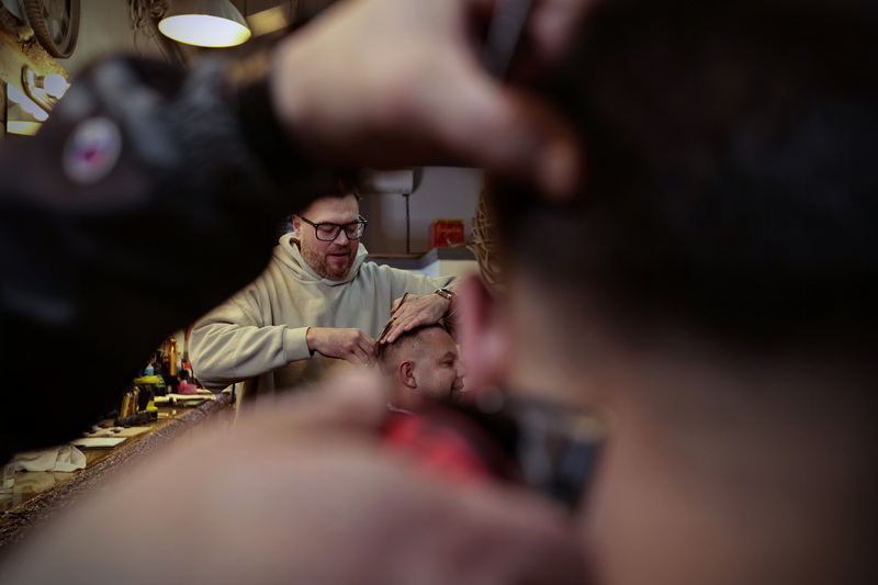 Jeff St. Pierre gives Rob McAuliffe a haircut as seen through the arms of Dennis Sykes giving Cole DeTerra a haircut with clippers at the New Bedford Barber Co. on William Street in New Bedford, MA. PHOTO PETER PEREIRA