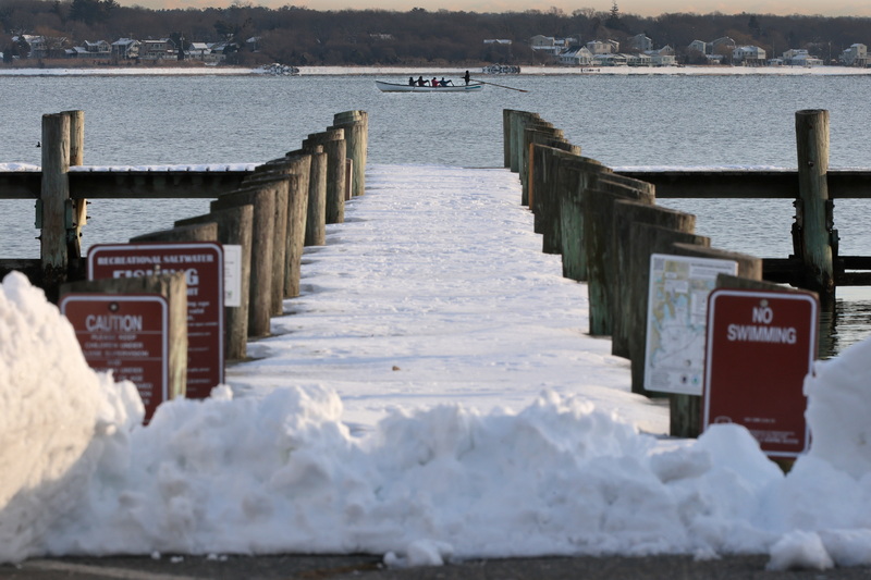 Members of the Whaling City Rowing Club make their way back into New Bedford harbor, past a frozen dock on East Rodney French Boulevard in New Bedford, during a morning row with temperatures hovering at eleven degrees.  This completes the 250th consecutive month the club rounded the Butler Flats Lighthouse during their morning row, a total of over 20 years of doing the six-mile row.