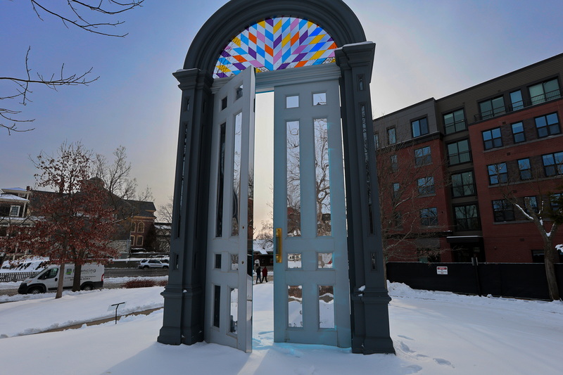 Two men walking up N Second Street are framed by the seventeen foot tall doorway art piece 'Threshold', at Custom House Square in New Bedford, MA on a cold morning. PHOTO PETER PEREIRA