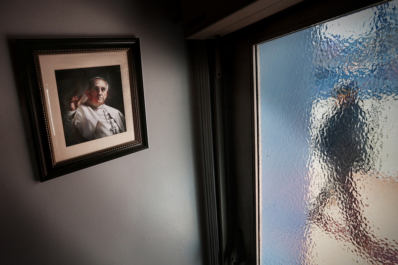 A picture of Pope Francis is displayed on the wall within Our Lady's Chapel on Purchase Street in New Bedford, MA while a man walks up Pleasant Street, passing by the frosted windows at the entrance of the downtown church. PHOTO PETER PEREIRA