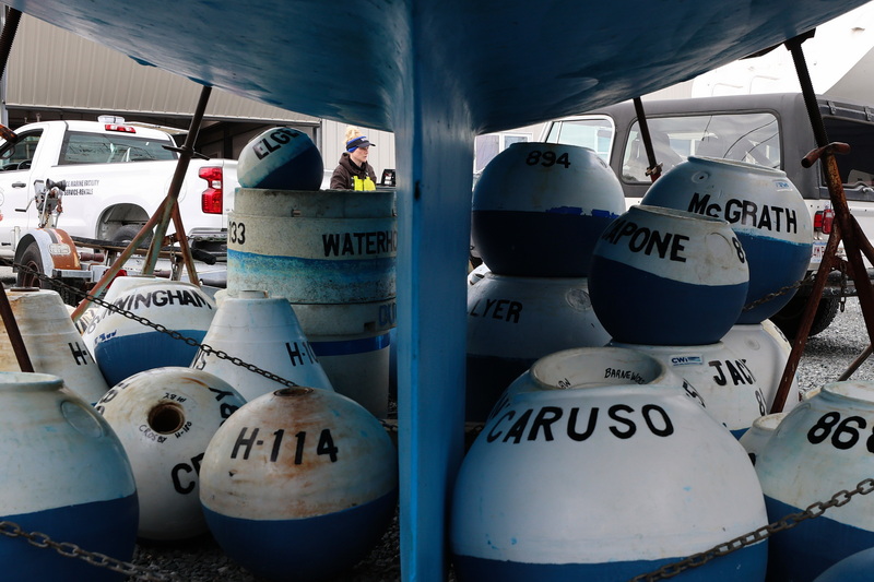 Becki Alden is seen between the keel of a sailboat and piles of moorings at Mattapoisett Boatyard, searching for the right mooring to install in the correct spot in Mattapoisett harbor as the winter 'sticks' are swapped out for the moorings needed for the boating season. PHOTO PETER PEREIRA