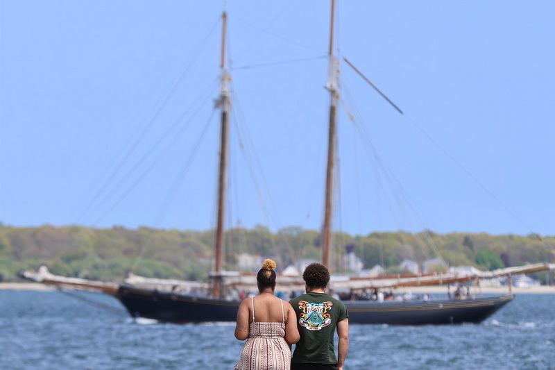 A couple enjoy the view from a dock on East Rodney French Boulevard as the schooner Ernestina-Morrissey makes its way back to into New Bedford harbor. PHOTO PETER PEREIRA