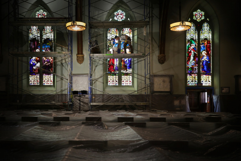 Carlos Queiroz and Higo Piero, paint the walls around the stained glass windows of the St. Lawrence Church on County Street in New Bedford, MA which is undergoing extensive interior repairs. PHOTO PETER PEREIRA