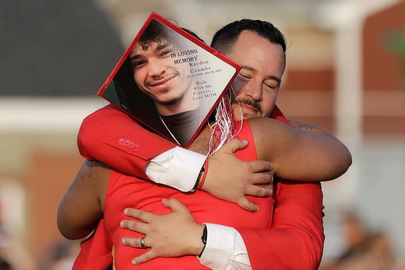 Kristie Rego hugs New Bedford High School associate principal, Jefferey Rego, upon receiving her son's diploma posthumously during the 2025 New Bedford High School graduation ceremony.  The mortarboard she is wearing a photo of her son Kayden Coombs who died earlier this year in a motor vehicle accident. PHOTO PETER PEREIRA