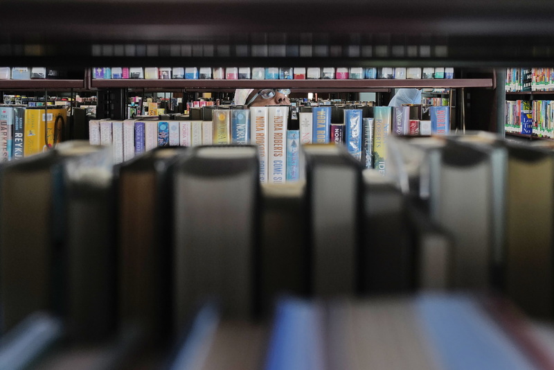 A woman is seen between lines of books as she browses the fiction shelves of the downtown New Bedford free public library for her next read. PHOTO PETER PEREIRA