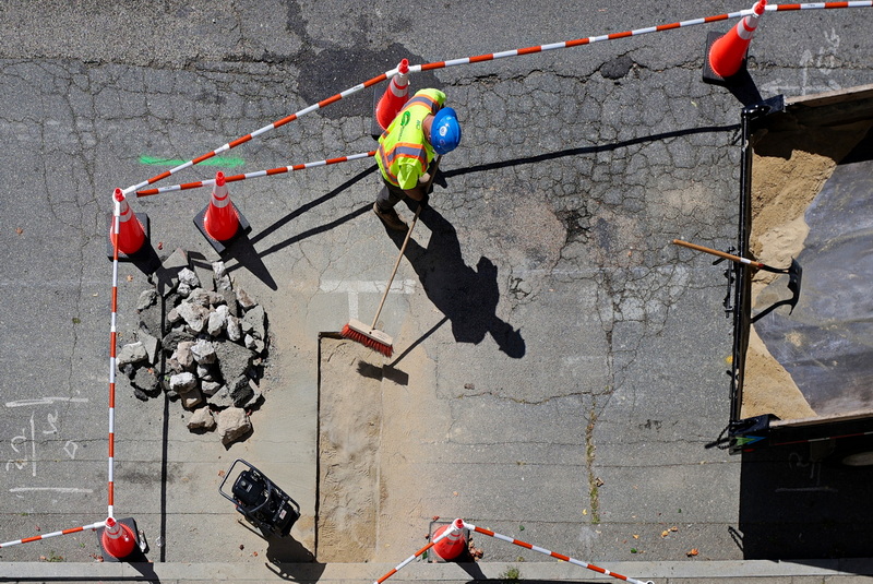 A worker has his shadow helping him fill in a hole dug up by the untilities company on School Street in New Bedford, MA PHOTO PETER PEREIRA