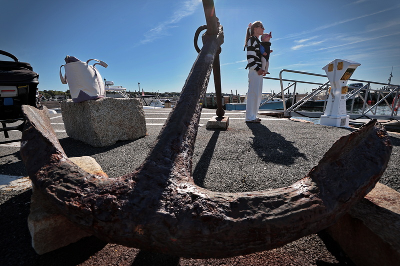 Lindsey Smith and her five-month-old daughter Prudence are waiting in Mattapoisett, MA for Lindsey's uncle to arrive by boat to take them for a weekend trip to Martha's Vineyard, with the famous anchor at the end of Holmes Wharf visible in the foreground. PHOTO PETER PEREIRA
