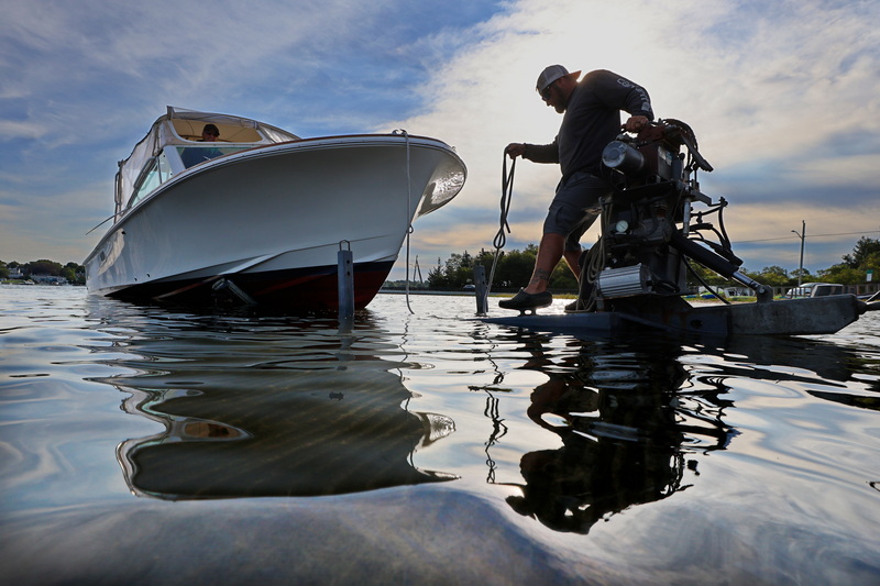 Chris Dumais, mooring manager with Concordia, gingerly walks across the frame of the boat trailer he is using to pull a boat from the water in Dartmouth, MA PHOTO PETER PEREIRA