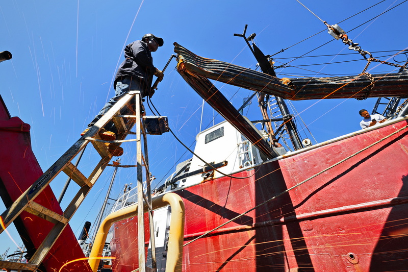 Blue Fleet welder Sal Sequeira sends sparks flying as he cuts the remnants of an outrigger mast bent in half aboard the Chatham fishing boat after hitting another fishing boat while out at sea. No one was hurt and it was able to complete the journey before returning to New Bedford harbor. PHOTO PETER PEREIRA