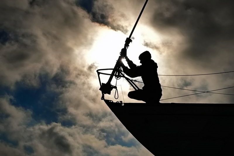 As the early morning sun emerges from behind the clouds, a Brownell Systems technician detaches the forestay from the hull of the sailboat being taken out of the water in Padanaram, Dartmouth. PHOTO PETER PEREIRA