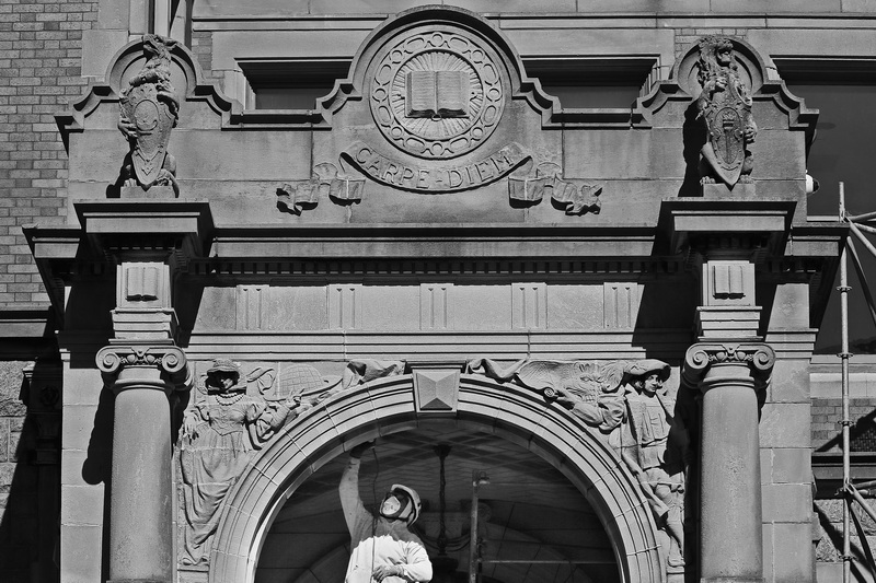 A mason seizes the moment to remove the grout from stonework of the iconic entrance to the Fairhaven High School building currently undergoing extensive an exterior restoration. PHOTO PETER PEREIRA