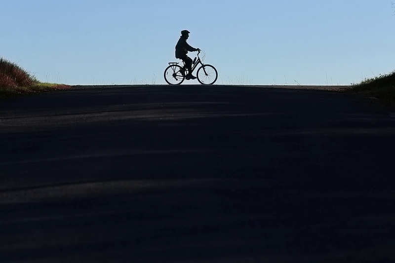 A man rides his bicycle on the crest of Horseneck Road as seen from Fisherville Lane in Westport, MA. PHOTO PETER PEREIRA