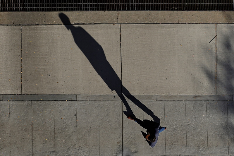 A man casts his shadow across the sidewalk as he makes his way up Elm Street as seen from the top of the Elm Street Parking Garage in New Bedford, MA. PHOTO PETER PEREIRA
