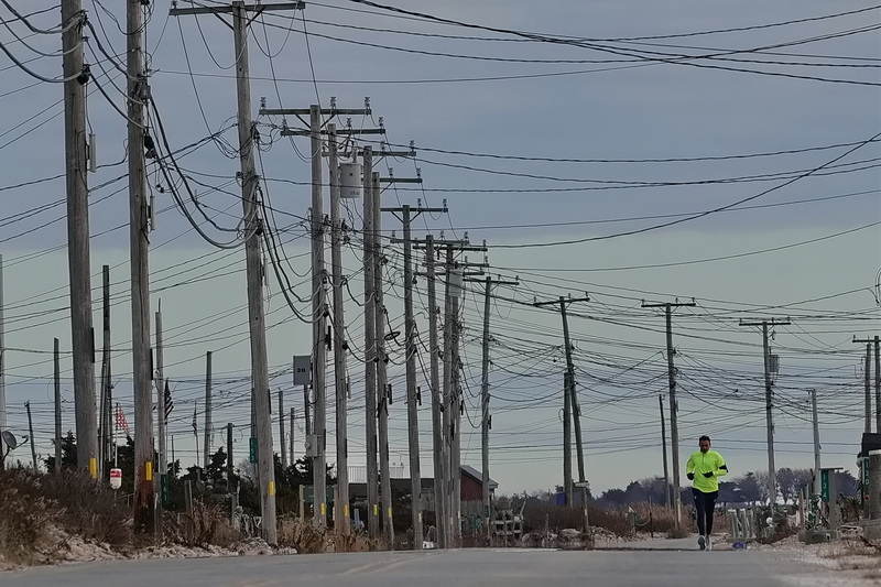 The utility poles create a crisscross of complexity above a man running on East Beach Road in Westport, MA. PHOTO PETER PEREIRA