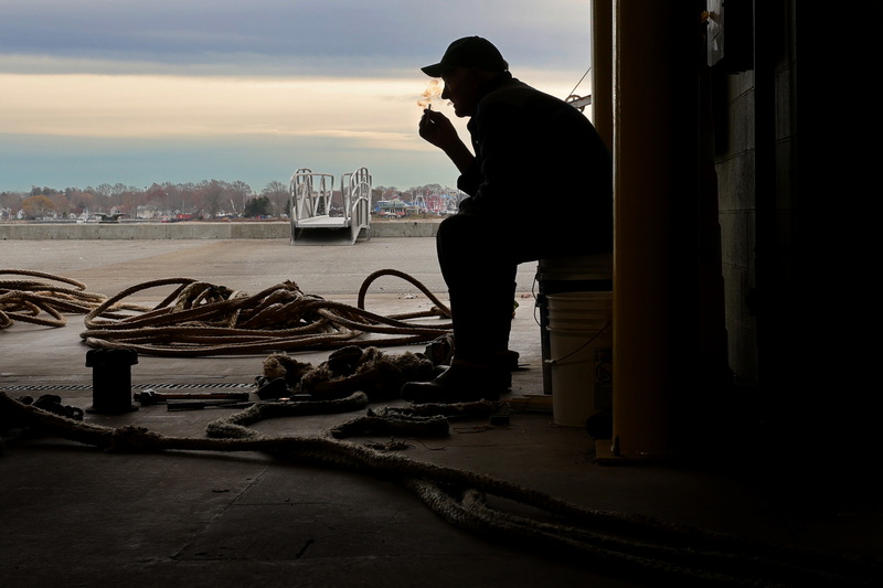 Inside the State Pier hanger in New Bedford, MA Ends Mullen takes a break from fixing the lines used to haul the herring net onto the fishing vessel he works on. PHOTO PETER PEREIRA
