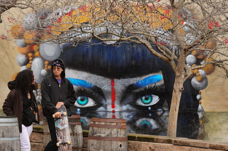 The newly painted mural on the side of a building keeps its eyes focused on the two people walking across Wings Court in New Bedford, MA. PHOTO PETER PEREIRA
