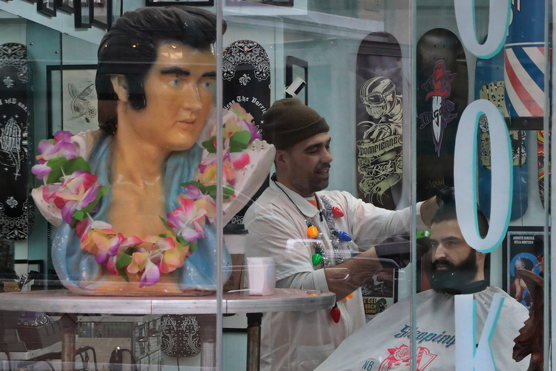 Elvis approves of the haircut which Denis Sykes is giving Jim Costa at the Stepping Razor barber shop in downtown New Bedford, MA. PHOTO PETER PEREIRA