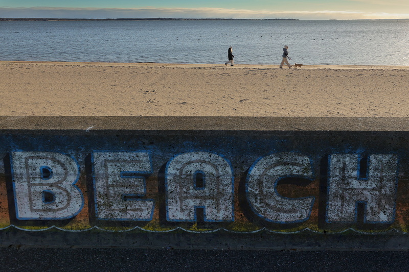 Two women and a small dog walk across East Beach in New Bedford, MA on a very cold morning. PHOTO PETER PEREIRA