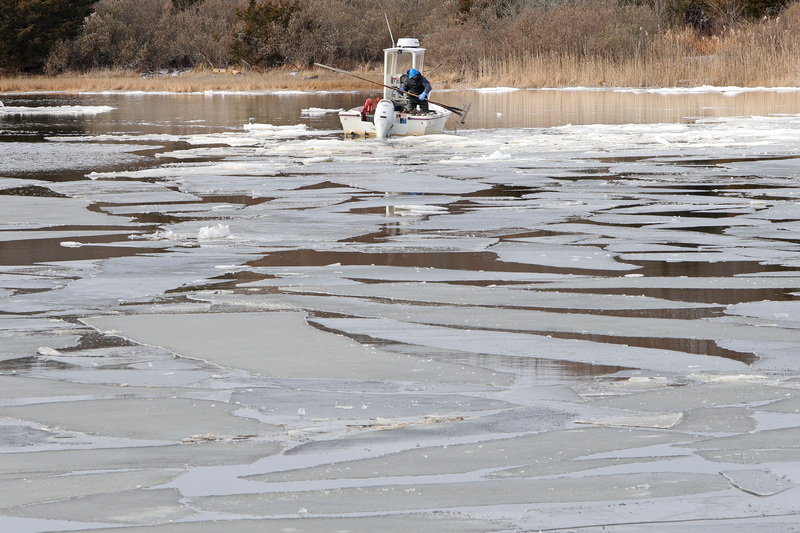Kevin Paiva uses a rake to break through the ice on the Westport River from his boat near Hix Bridge to dig for quahogs, as the shellfishing season begins in Westport, MA. PHOTO PETER PEREIRA