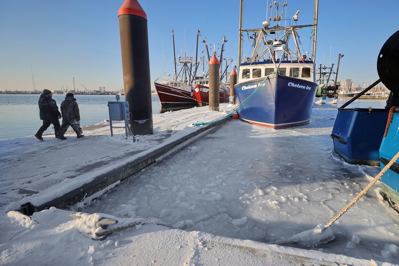 Two men walk along the dock at Fleet Marina in New Bedford, MA surrounded by a frozen harbor on a frigid morning. PHOTO PETER PEREIRA