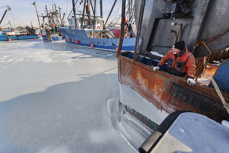 Bob Bowers of C&P Fuels looks out into a frozen New Bedford harbor as he refuels a fishing boat docked in Fairhaven, MA. PHOTO PETER PEREIRA