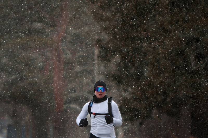 A woman running around Buttonwood Park in New Bedford, MA finds herself surrounded by unexpected falling snow. PHOTO PETER PEREIRA