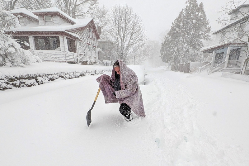 Lauren Bonnet wades through the deep snow as she tries to make her way to her car to retrieve her jacket as a blizzard makes its way across New Bedford, MA. PHOTO PETER PEREIRA