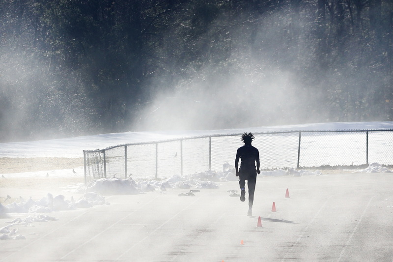 The heat evaporates the snow from the track at UMass Dartmouth as a student athlete performs his morning training routine. PHOTO PETER PEREIRA