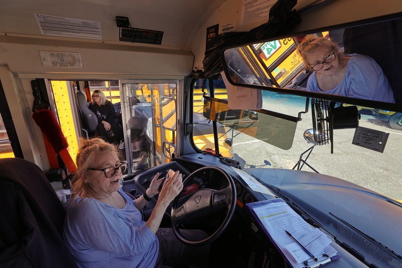 Colleen Catanho, seated below, and fellow Tremblay bus driver Malinda Machado, seated above, park side by side to chat after dropping off students from Pulaski Elementary School and Carney Academy at The Zeiterion in New Bedford for a symphony orchestra show. PHOTO PETER PEREIRA