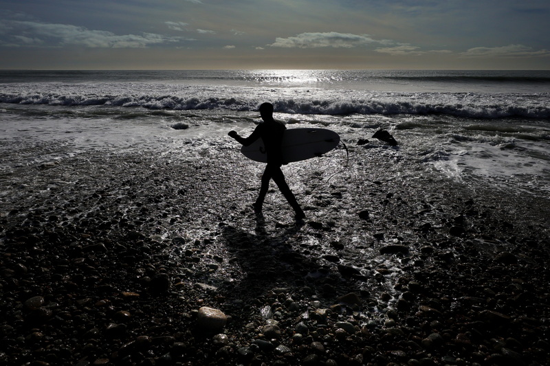 Trent Souza goes to surf the waves formed by the weather front that passed through the region, at East Beach in Westport, MA.  PHOTO PETER PEREIRA