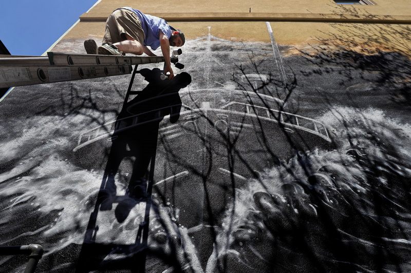 Ryan Mcfee paints a fishing boat mural on the wall at Wings Court in downtown New Bedford, MA. PHOTO PETER PEREIRA