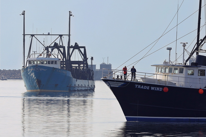 Two fishermen stand on the bow of the fishing boat Trade Wind as they and the E.S.S. Pride wait for the Fairhaven bridge to open to cross into New Bedford's North harbor. PHOTO PETER PEREIRA