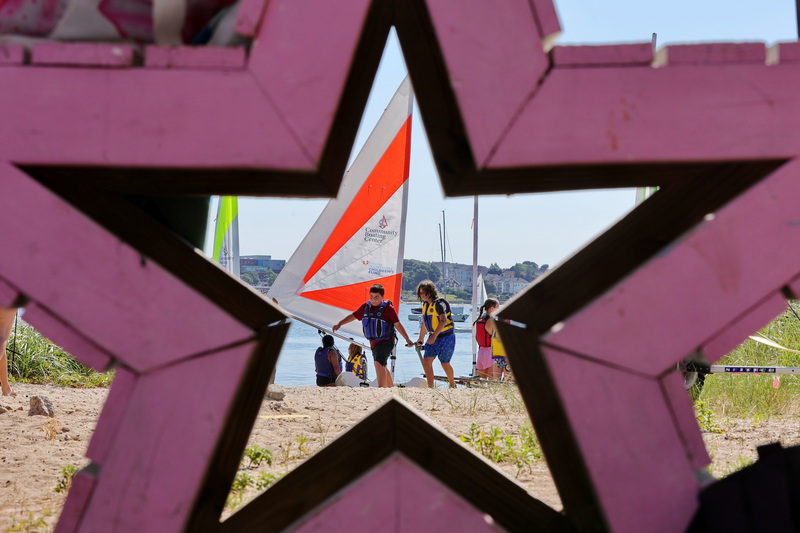 Students launch their Zest sailboats, which were donated by the Montigny Children's Fund and the Yawkey Foundation, into the water for a day of sailing on July 13, 2026, at the Community Boating Center in New Bedford, MA, viewed through a star-shaped bench. PHOTO PETER PEREIRA