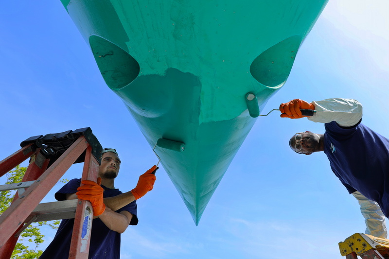 Noah Pittsley and Will Cruz paint the hull of a sailboat on July 14, 2026 at Barden's Boat Yard in Marion, MA. PHOTO PETER PEREIRA