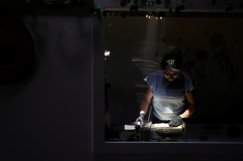 A ray of light shines on Vanessa Dos Santos, owner of Eden Coffee & Bakery, as she rolls dough for croissants at her coffee shop in Mattapoisett, MA on July 17, 2026. PHOTO PETER PEREIRA