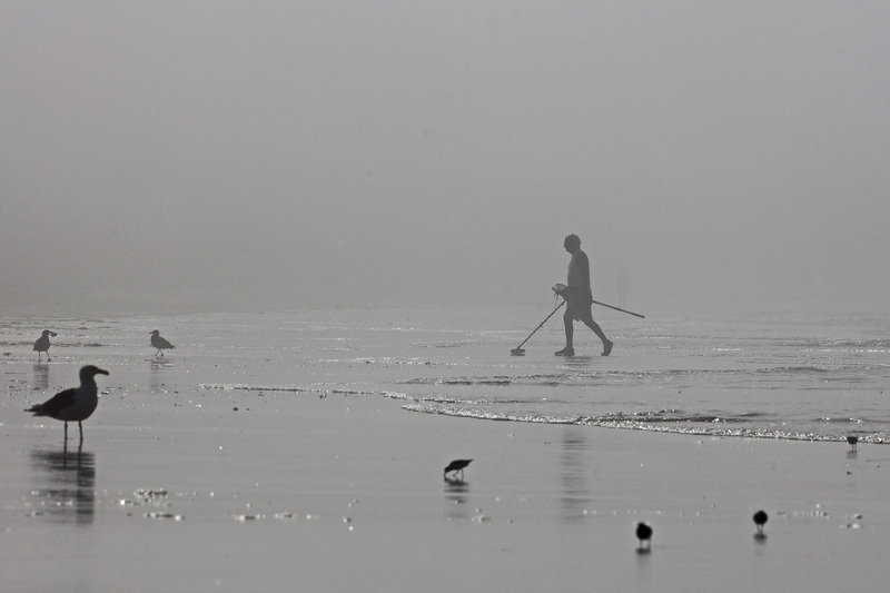 A man scans the beach with a metal detector on a hot, hazy morning at Horseneck Beach in Westport, MA on August 7, 2026. PHOTO PETER PEREIRA