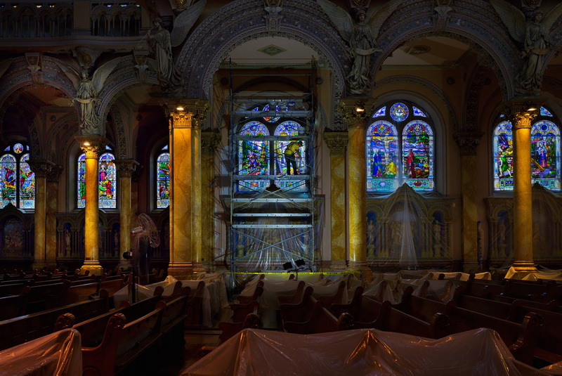 On August 18, 2026, a painter is seen painting the frame surrounding a large stained glass window inside the St. Anthony of Padua church in New Bedford, MA. The historic church is currently undergoing significant interior restoration. PHOTO PETER PEREIRA
