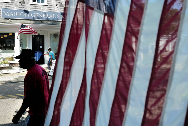 A patron reaches for the door of the Marion General Store on Front Street in Marion, MA on August 19, 2026 as another walks across the street. PHOTO PETER PEREIRA